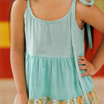 Girl wearing organic cotton dress with aqua blue top and block print skirt, sleeveless with tie straps