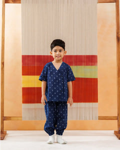 Smiling young boy in navy blue organic cotton kurta pajama with small block print pattern, standing indoors.