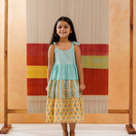 Young girl wearing sleeveless tiered cotton dress with floral and block print patterns