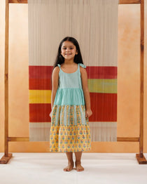 Young girl wearing sleeveless tiered cotton dress with floral and block print patterns