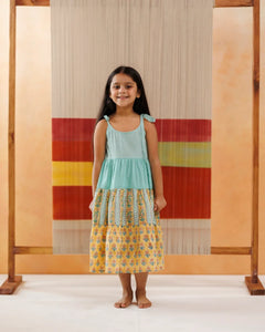 Young girl wearing sleeveless tiered cotton dress with floral and block print patterns