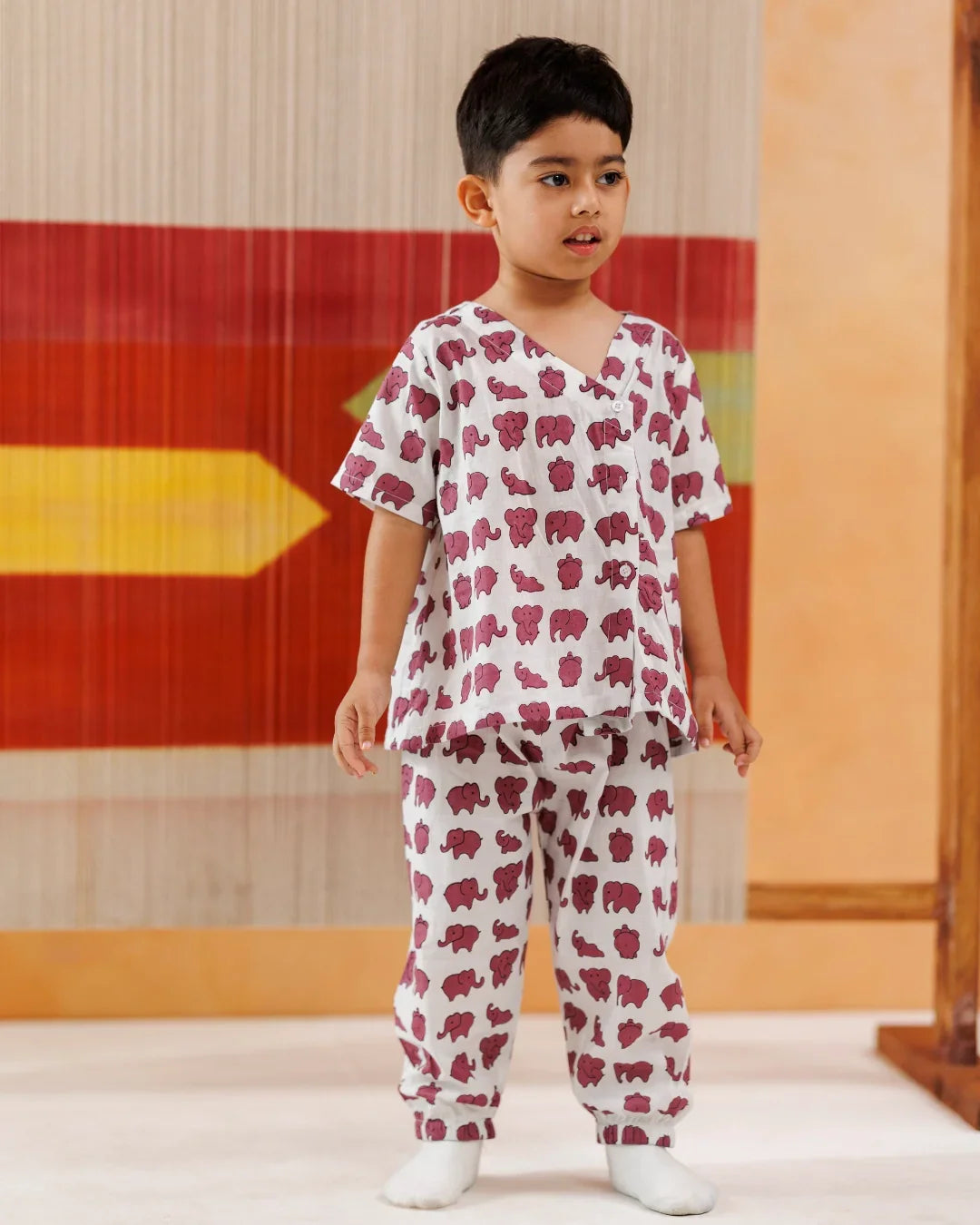 Young child wearing organic cotton kidswear pajamas with purple elephant print