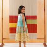 Young girl in a sleeveless block print cotton dress with floral patterns, standing indoors