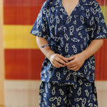 Child wearing navy blue organic cotton shorts set with cream fish print, standing indoors