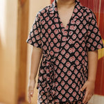 Smiling toddler in organic cotton block print wrap top and pants set, black with red pattern