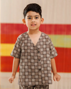 Young boy in brown organic cotton block print shirt and shorts, colorful background