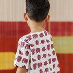 Toddler in white organic cotton t-shirt with pink elephant print, colorful background