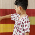 Young child in white shirt with purple elephant print, standing against striped background