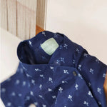 Navy blue organic cotton kids shirt with white block print floral pattern hanging by loom.