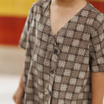 Child wearing a brown organic cotton shirt with abstract block print and v-neck design