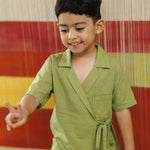 Smiling boy in green organic cotton wrap top and shorts, kidswear, playing indoors