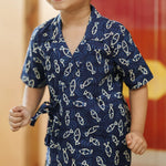 Smiling child in navy blue organic cotton shirt with white fish pattern, playful kidswear
