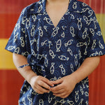Child wearing blue organic cotton shirt with white fish pattern, short sleeves, summer kidswear