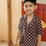 Smiling young boy in black organic cotton block print wrap top and shorts set