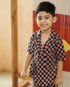 Smiling young boy in black organic cotton block print wrap top and shorts set