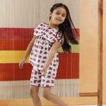 Girl in organic cotton elephant print shorts set, sustainable kidswear, playful setting