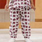 Child wearing white organic cotton pajamas with purple elephant print, standing indoors