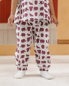 Child wearing white organic cotton pajamas with purple elephant print, standing indoors
