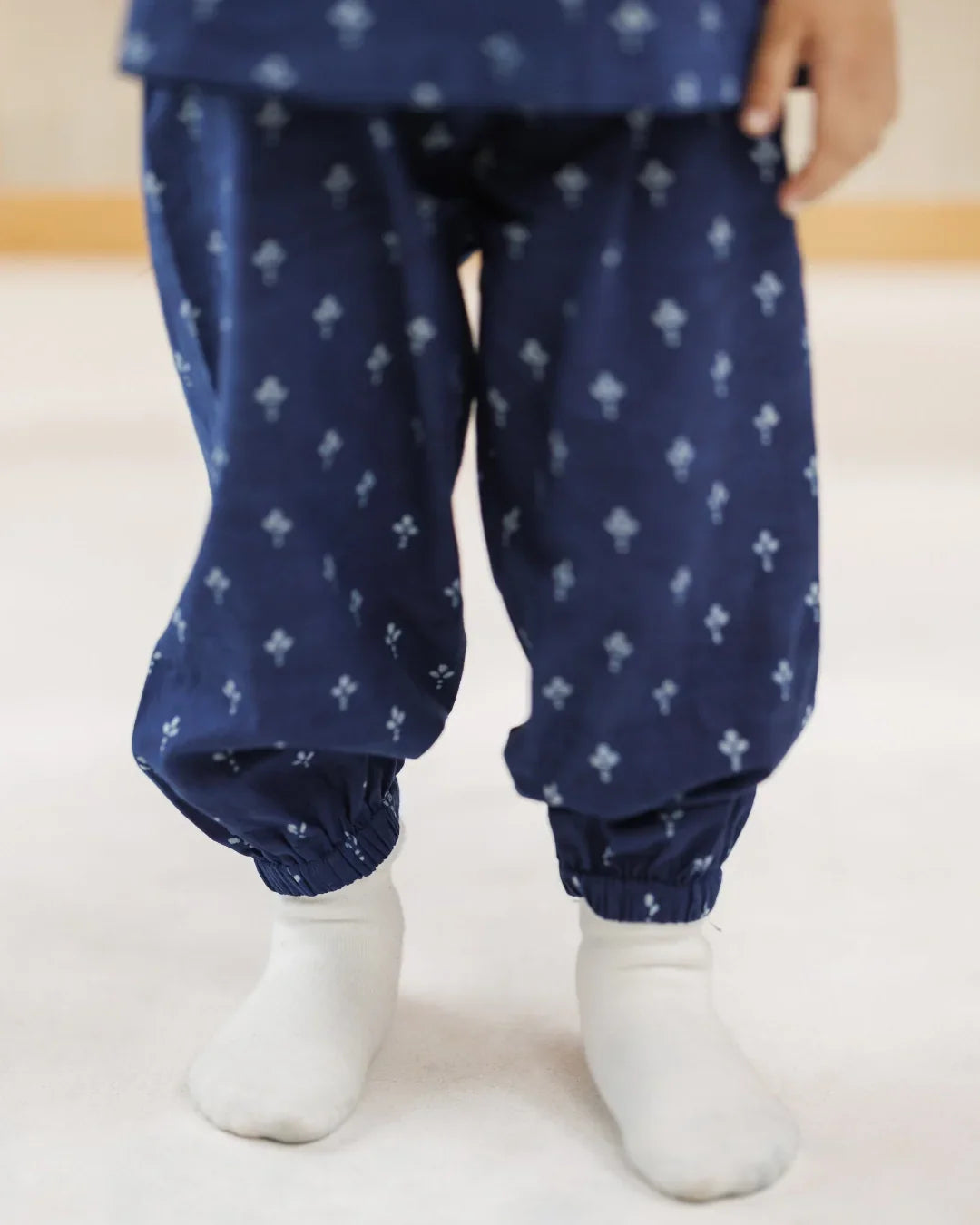 Child in organic cotton blue block print pants with elastic cuffs, white socks