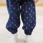 Child in organic cotton blue block print pants with elastic cuffs, white socks