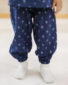 Child in organic cotton blue block print pants with elastic cuffs, white socks