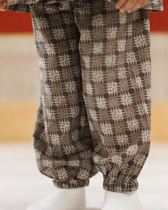 Child wearing loose-fit organic cotton pants with brown geometric block print pattern