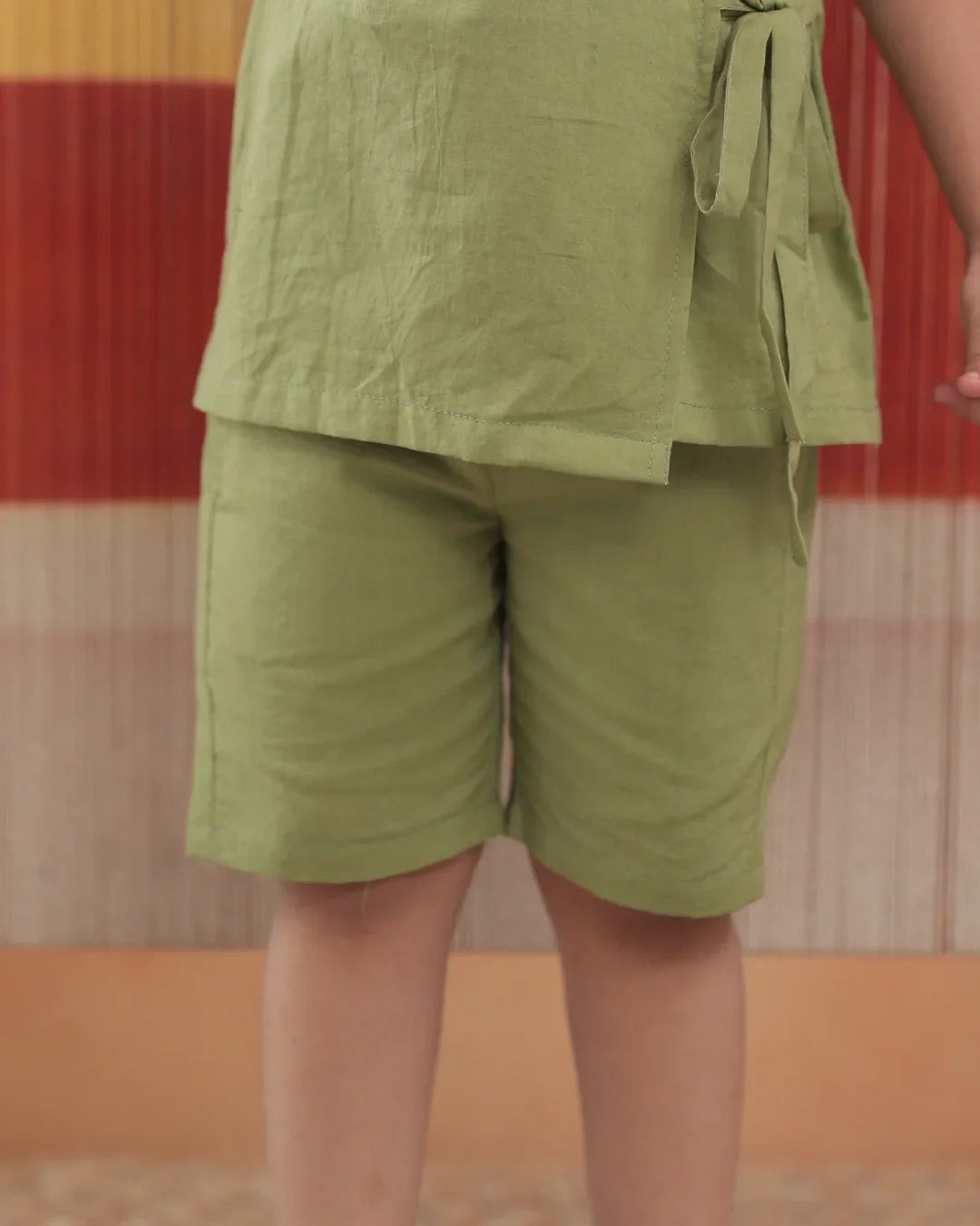 Child wearing light green organic cotton shorts and top set, sustainable kidswear