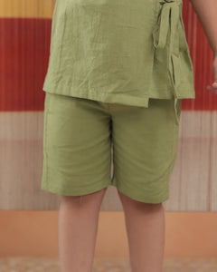 Child wearing light green organic cotton shorts and top set, sustainable kidswear