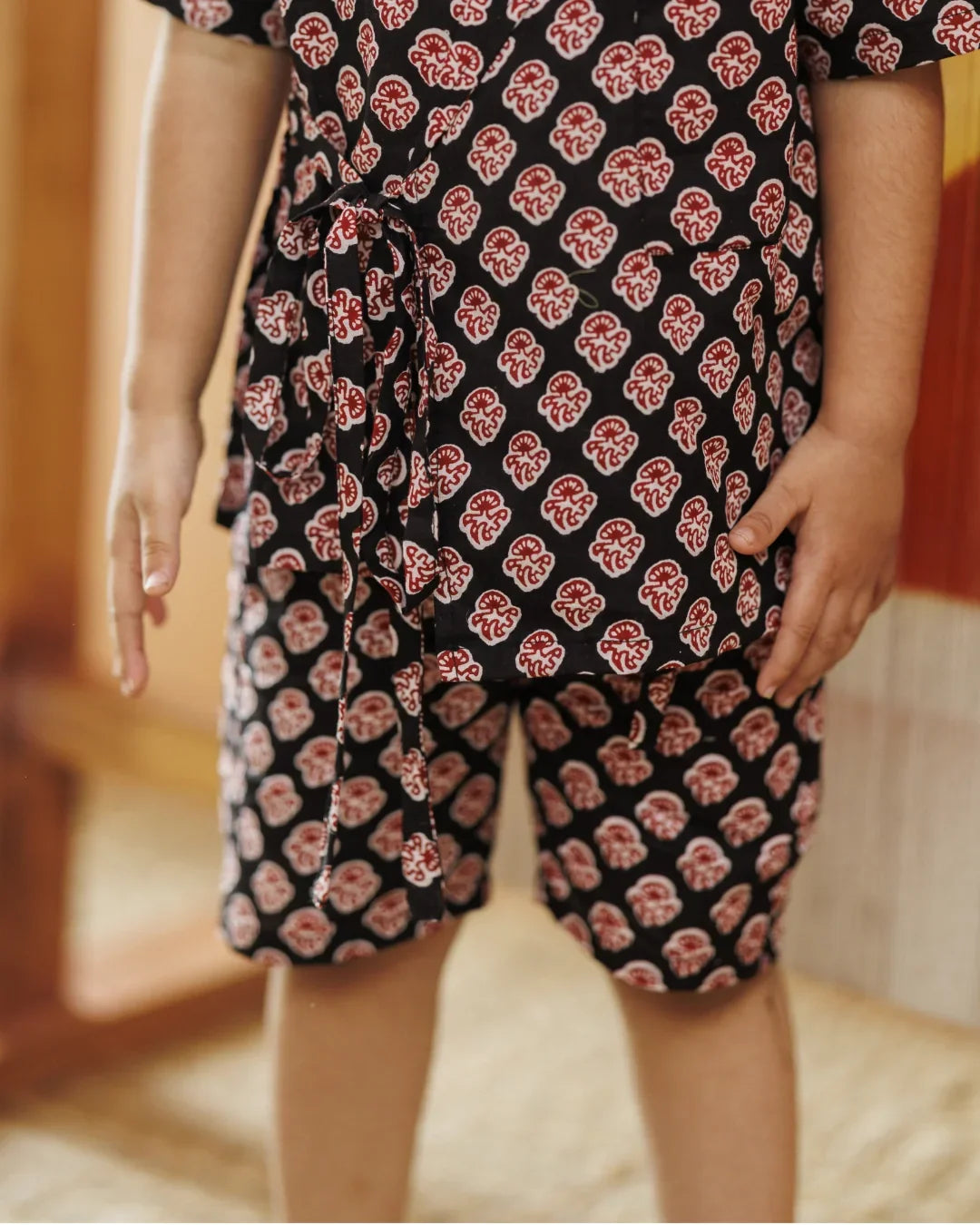 Child wearing black organic cotton shorts and top set with red block print pattern