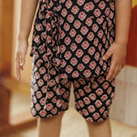 Child wearing black organic cotton shorts and top set with red block print pattern