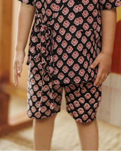 Child wearing black organic cotton shorts and top set with red block print pattern
