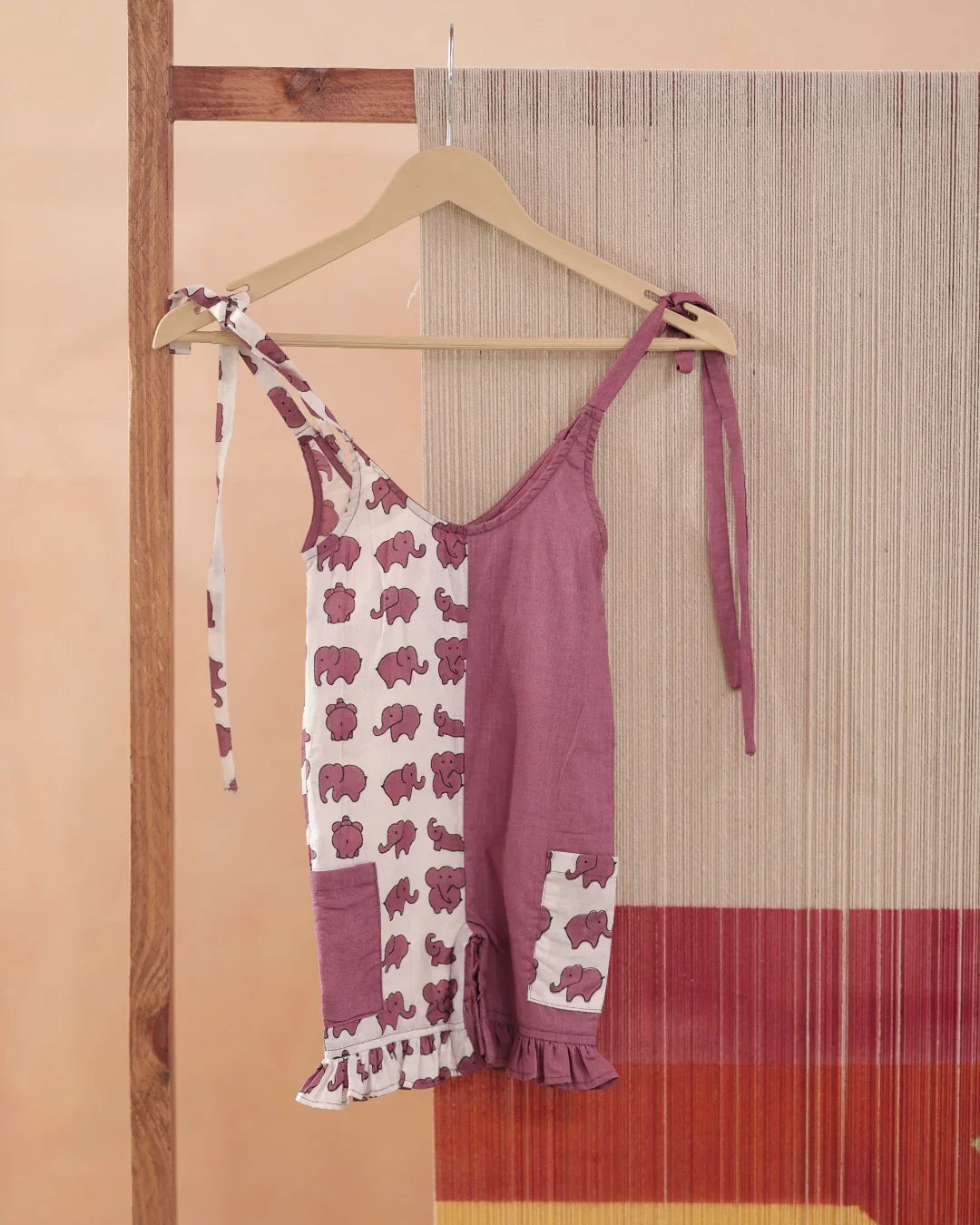 Organic cotton kids romper, half mauve, half white with pink elephant print, on hanger