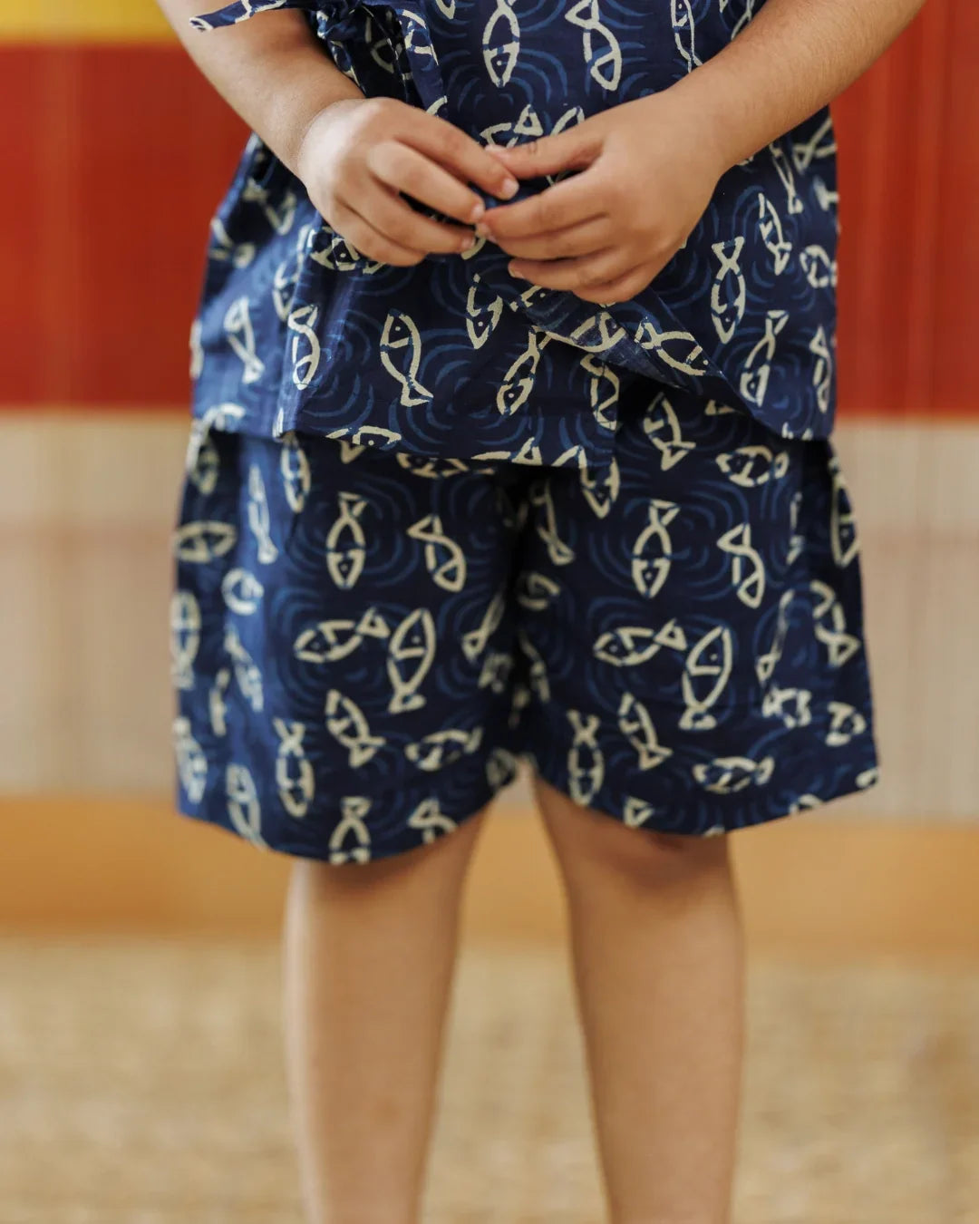 Child wearing blue organic cotton shorts and top with fish print pattern