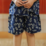 Child wearing blue organic cotton shorts and top with fish print pattern