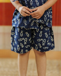 Child wearing blue organic cotton shorts and top with fish print pattern